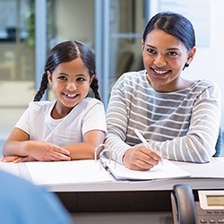 Smiling mother and daughter checking in at dental reception desk
