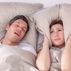 man snoring and woman covering her ears