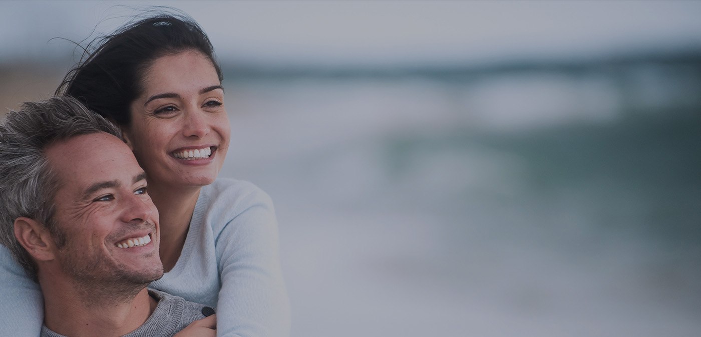 Smiling man and woman holding each other outdoors