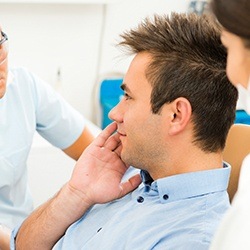 Man in dental chair holding cheek