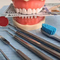 dental model with money between teeth and dental tools