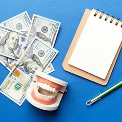 money, teeth, and paper and pencil on a blue background