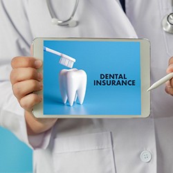 dentist holding a tablet with dental insurance on the screen