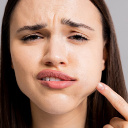 pained woman pointing to her swollen face 