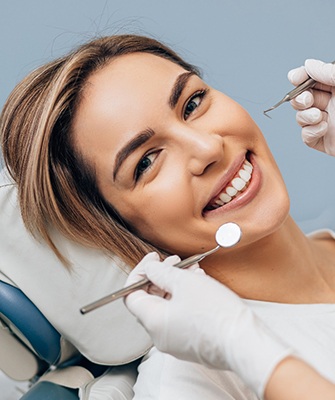 patient smiling with dental instruments close to her face