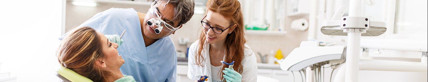 Dentist and team member helping patient in dental chair