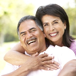 couple smiling and hugging with implant dentures in Westhampton