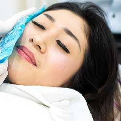 woman with a cold compress on her face to deal with the side effects of implant placement