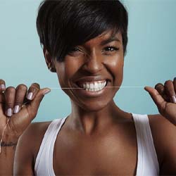 woman flossing her teeth to maintain oral hygiene after implants in Westhampton