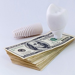 Model implant and money representing the cost of dental implants in Westhampton