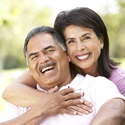 Laughing couple with beautiful smiles thanks to dental implants in Westhampton 