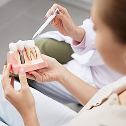 Patient learning about dental implants in Westhampton via model