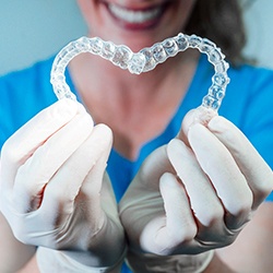 gloved hands holding Invisalign in a heart shape