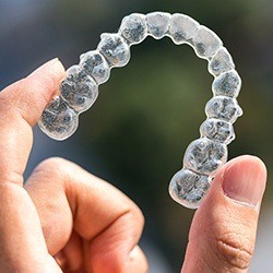 Hand holding up Invisalign tray