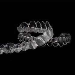 Invisalign aligners against black background covered by dental insurance