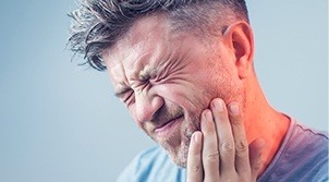 Man in pain holding cheek