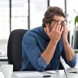 Tired man with head in hands at work