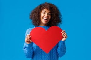 woman smiling and holding a heart for heart health month