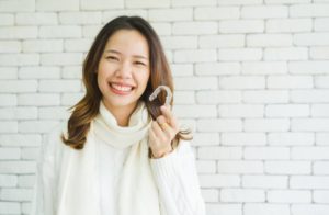 woman smiling holding an Invisalign aligner