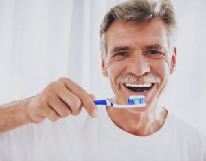 elderly man brushing his teeth and following dental hygiene tips