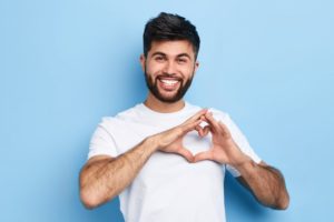 man smiling and forming a heart shape with his hands