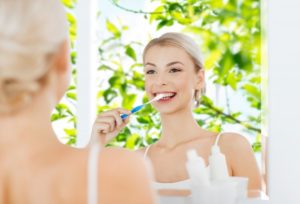 woman brushing her teeth with spring in the background