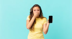 woman holding her phone after seeing popular trends that are bad for teeth