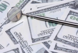 dental instrument on top of a pile of money showing how the dentist can save you money