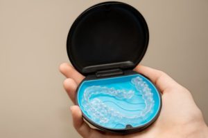 hand holding clear aligners in the case