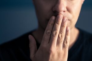 closeup of a man covering his mouth