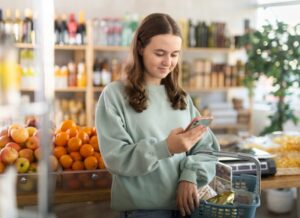 young woman looking at her phone in the grocery store