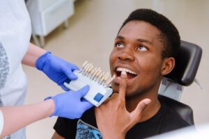 patient pointing to his teeth with a color guide next to him