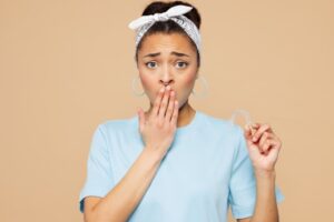 worried woman holding her Invisalign aligner