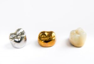 two metal crowns and a ceramic one with a white background