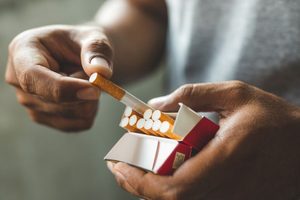 Person removing cigarette from pack